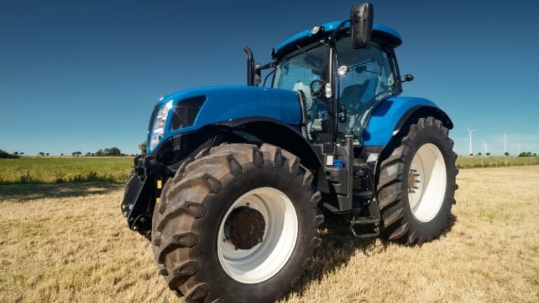 A modern blue utility tractor on farmland, showing one of the best tractor options for 50-acre farms