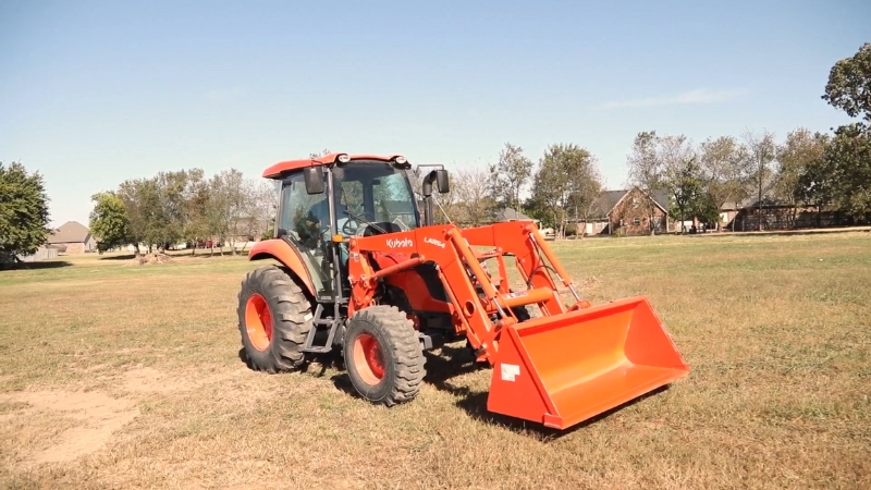 Kubota M7060 tractor with front loader parked on farmland, ideal for 50-acre farm operations