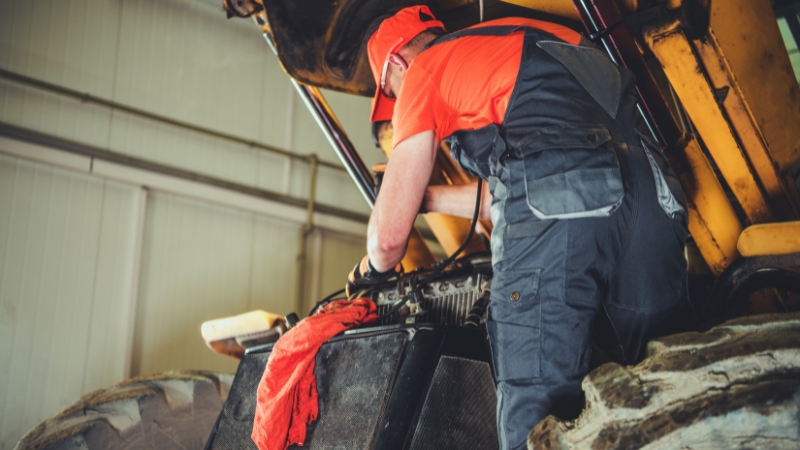 A mechanic works on a tractor engine
